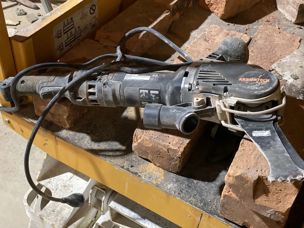 a dusty arbortech saw sitting on antique bricks in a historic building renovation jobsite