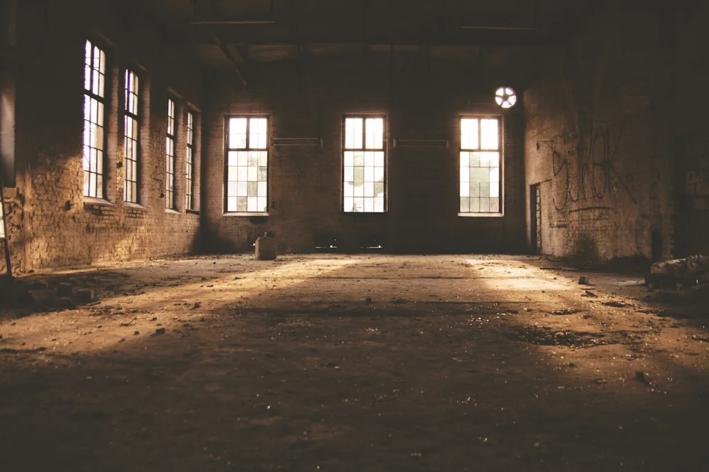 the inside of a long-abandoned commercial building with factory-style windows and brick walls.